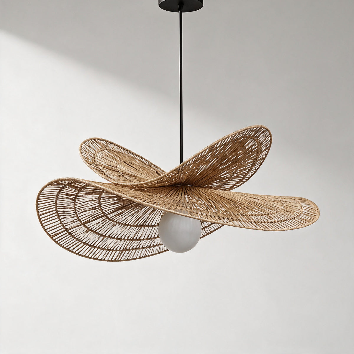 Isla Chandelier, hand-woven natural rattan pendant with two wavy brims and a frosted globe, studio front view