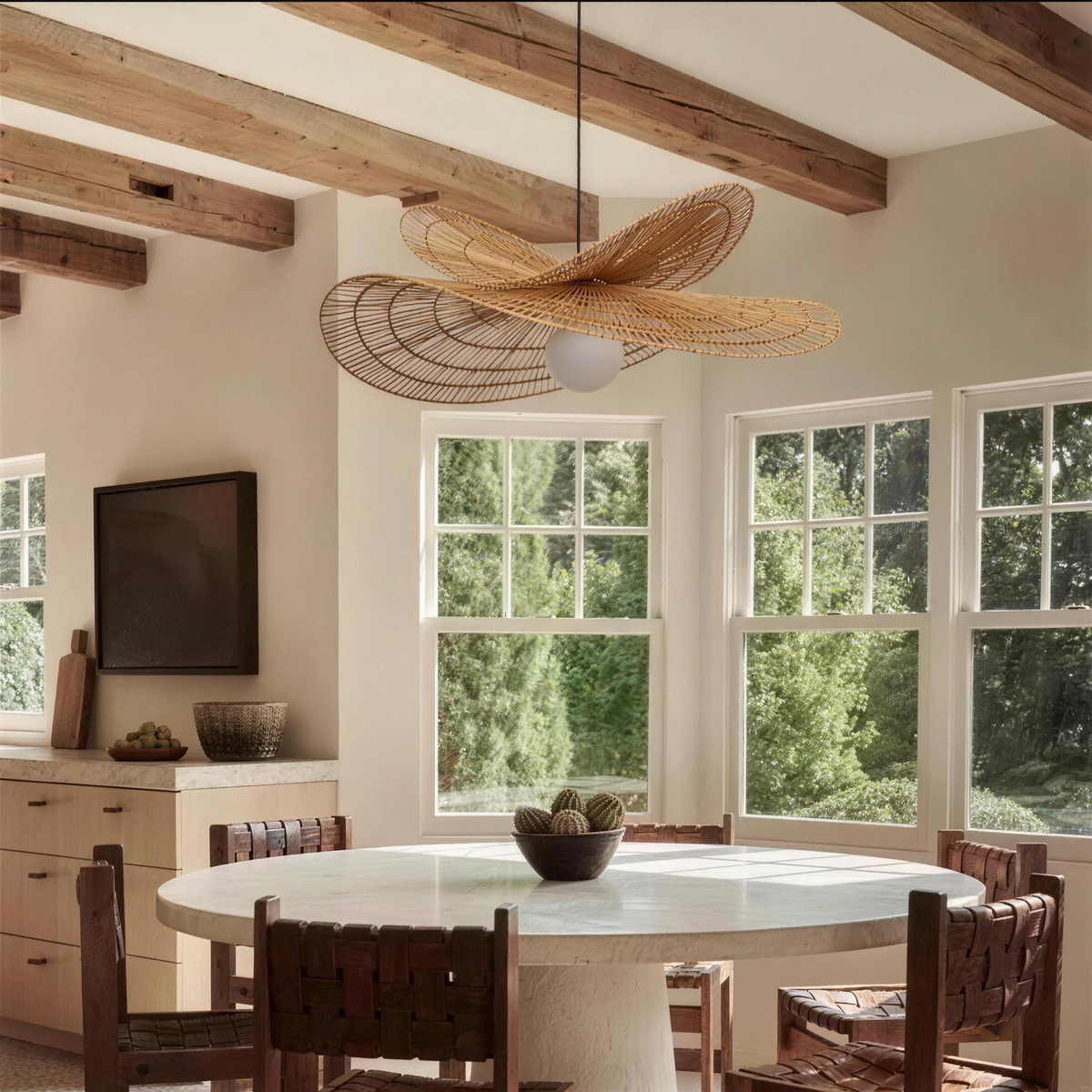 Isla rattan chandelier over a round dining table in a bright kitchen with wooden beams