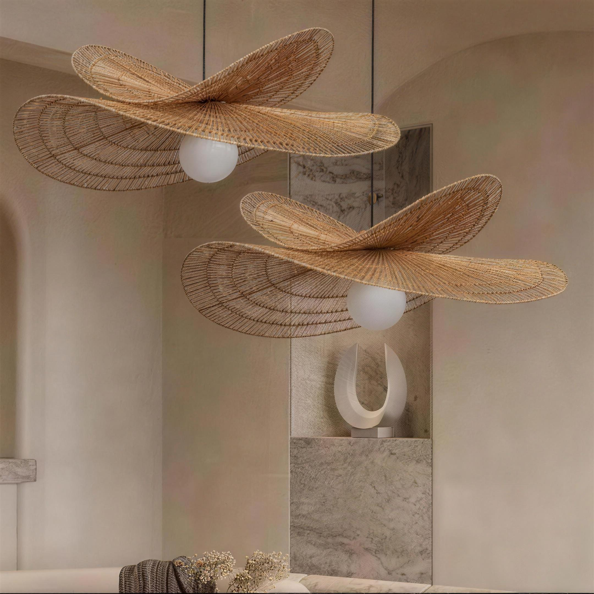 Two Isla rattan chandeliers hanging in a plaster stairwell