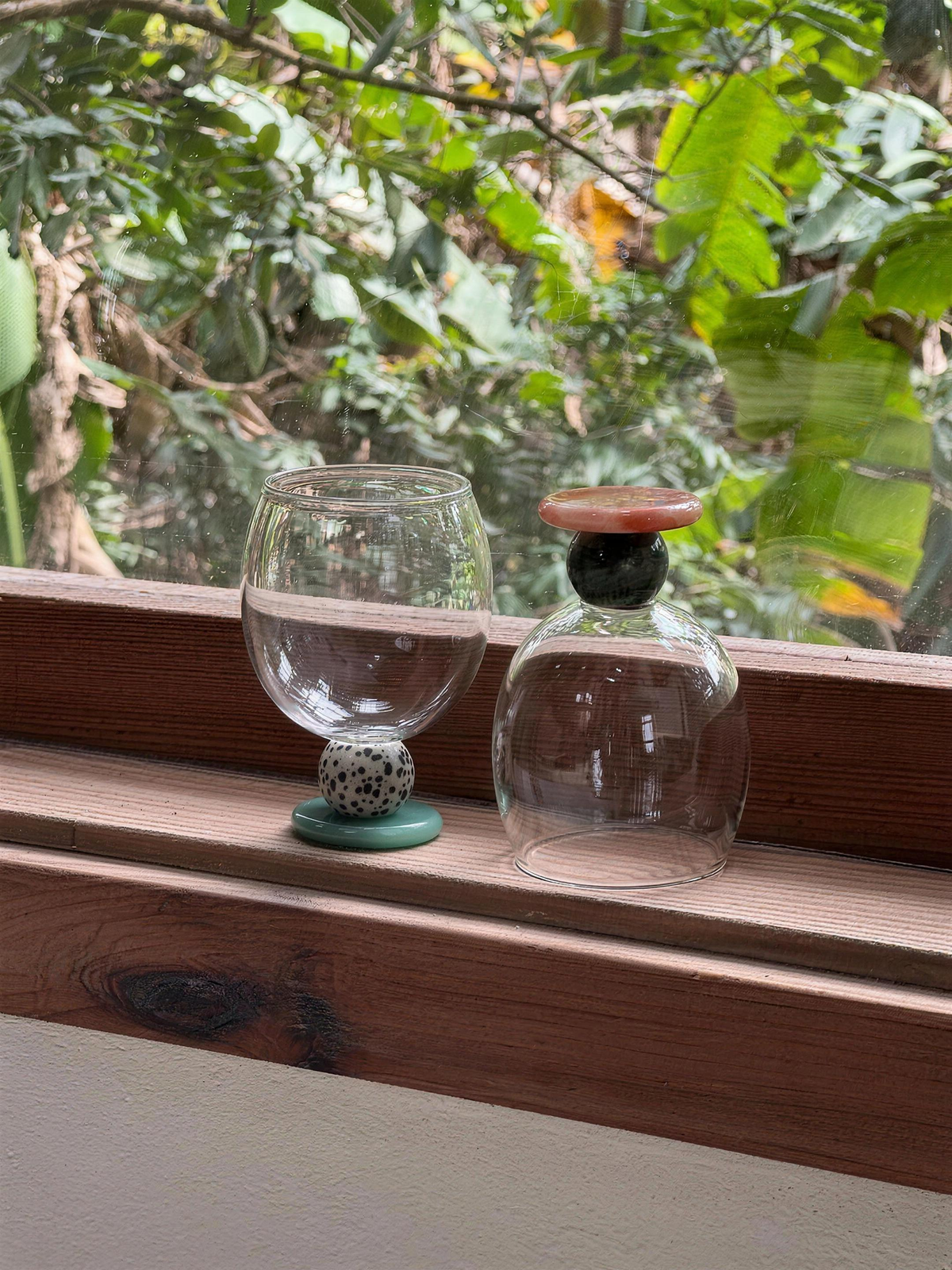 Panarea goblets on a wooden sill with green leaves outside