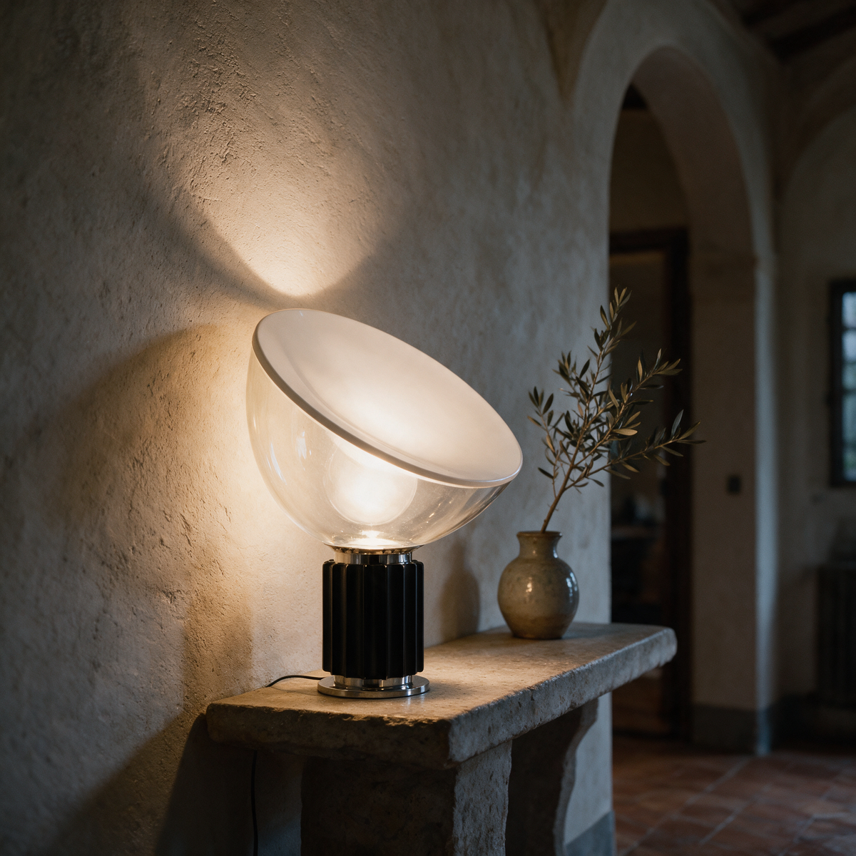 Luca Table Lamp, black, on a stone console in a plaster hallway