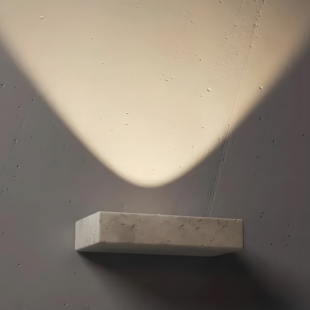 Maelle wall-mounted travertine lamp, front view showing warm ambient light