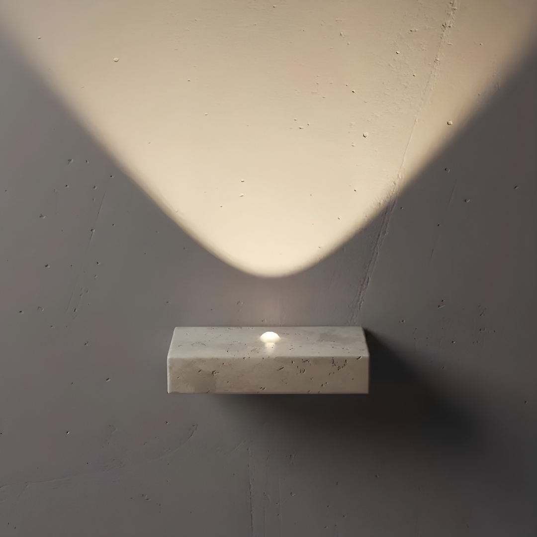 Maelle travertine wall sconce mounted on wall, side angle