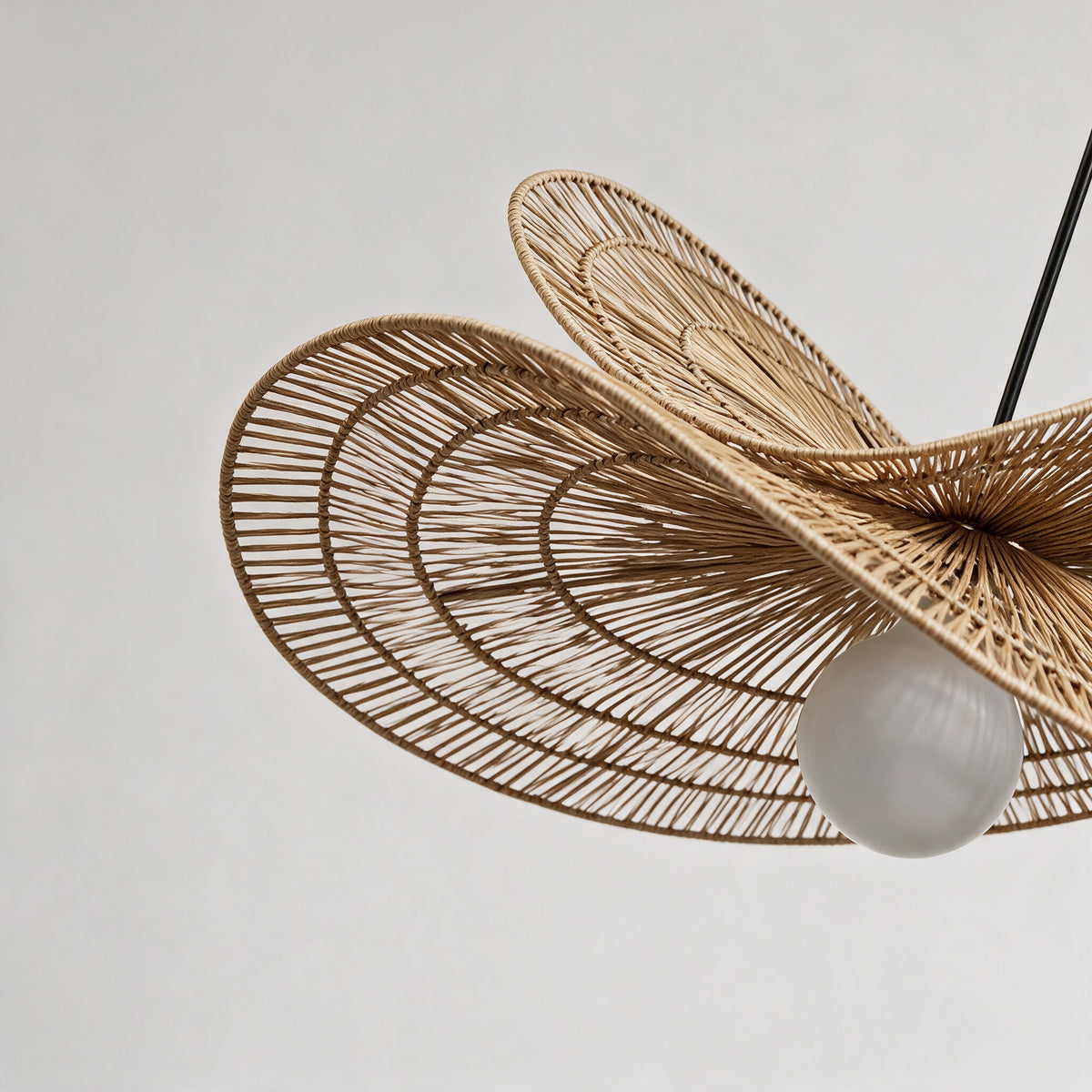 Close-up of the hand-woven rattan brims and frosted globe of the Isla Chandelier