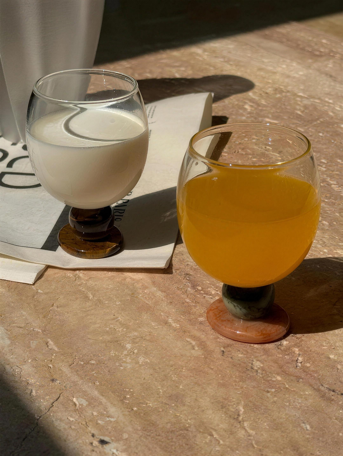 Milk and orange juice in Panarea goblets on a travertine table